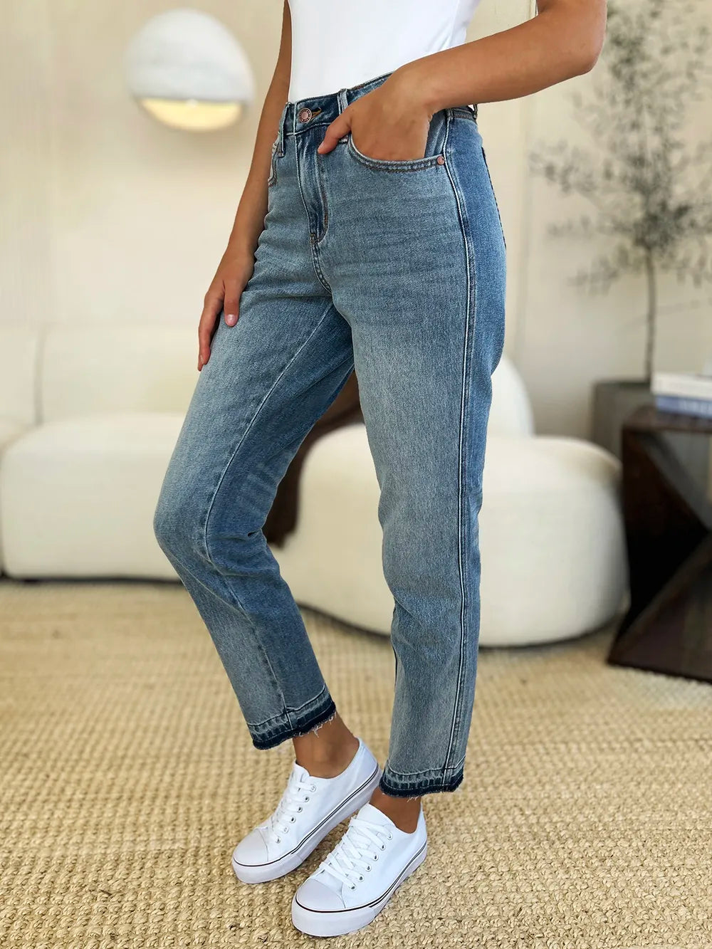 Person wearing blue jeans and white sneakers in a living room setting
