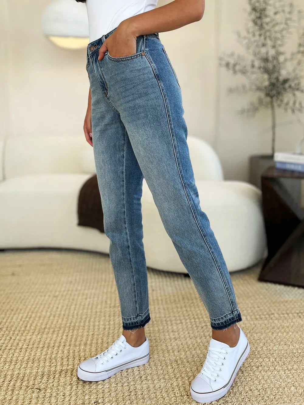 Person wearing blue jeans and white sneakers in a living room setting