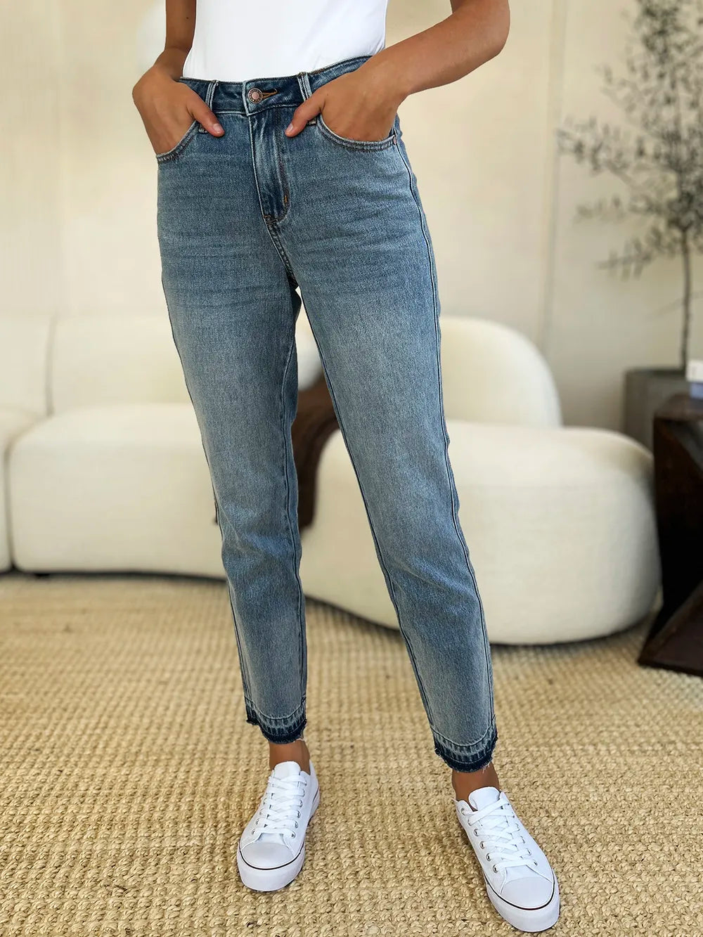 Person wearing blue jeans and white sneakers in a living room setting