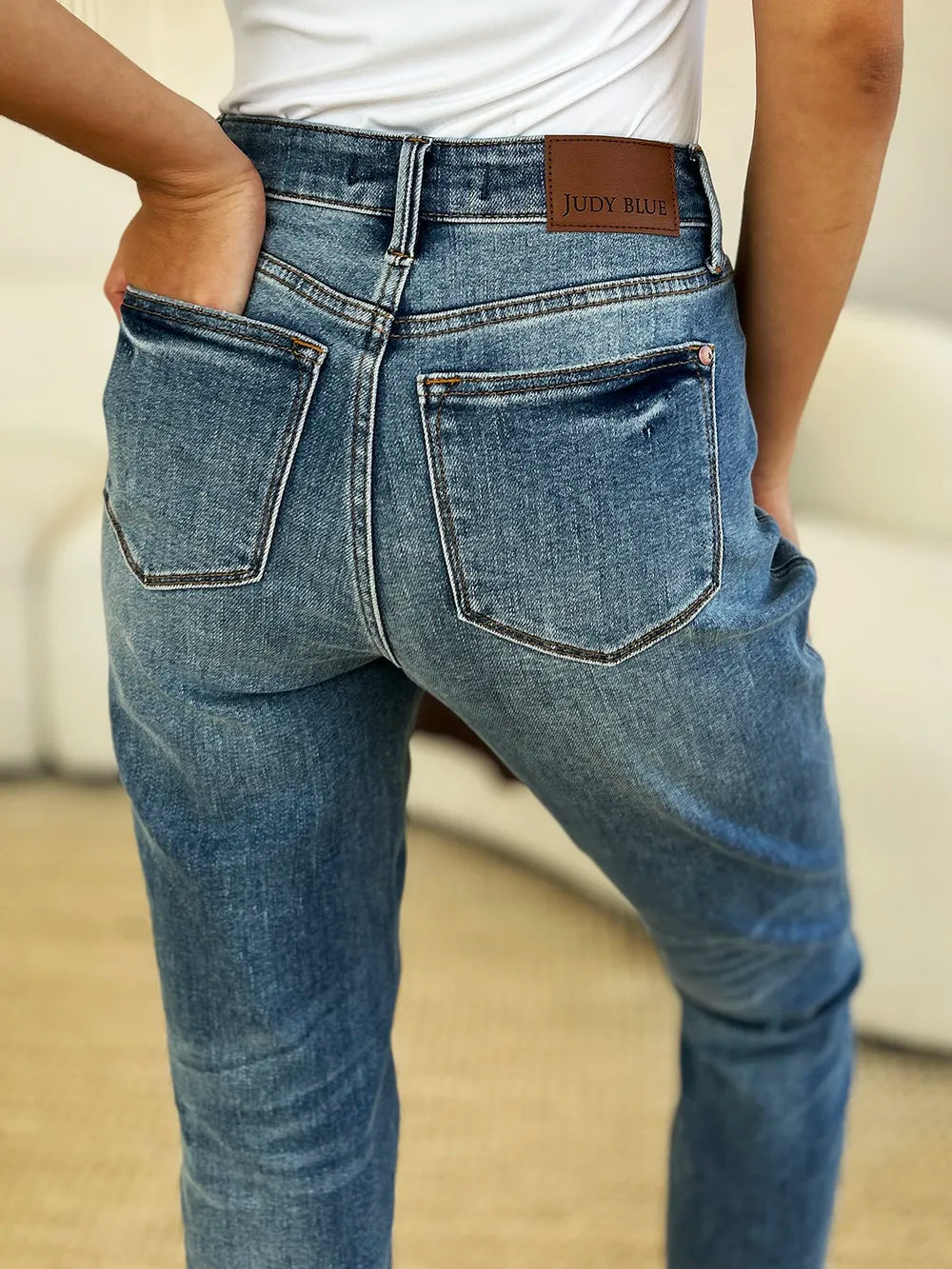 Person wearing blue jeans with a visible brand label on a neutral background
