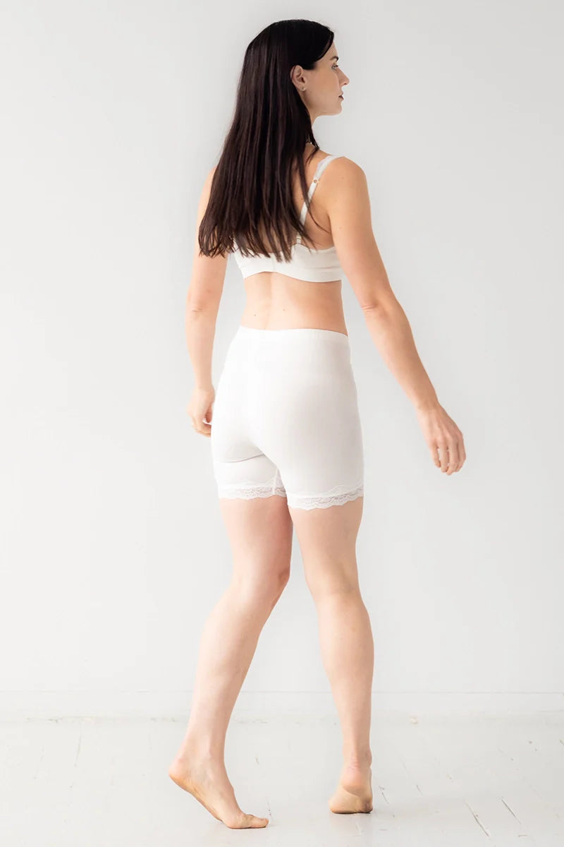 Woman wearing a white sports bra and shorts on a white background