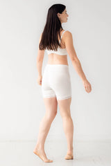 Woman wearing a white sports bra and shorts on a white background