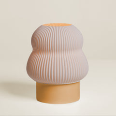 Decorative vase with ribbed design and mustard yellow base on a light beige background