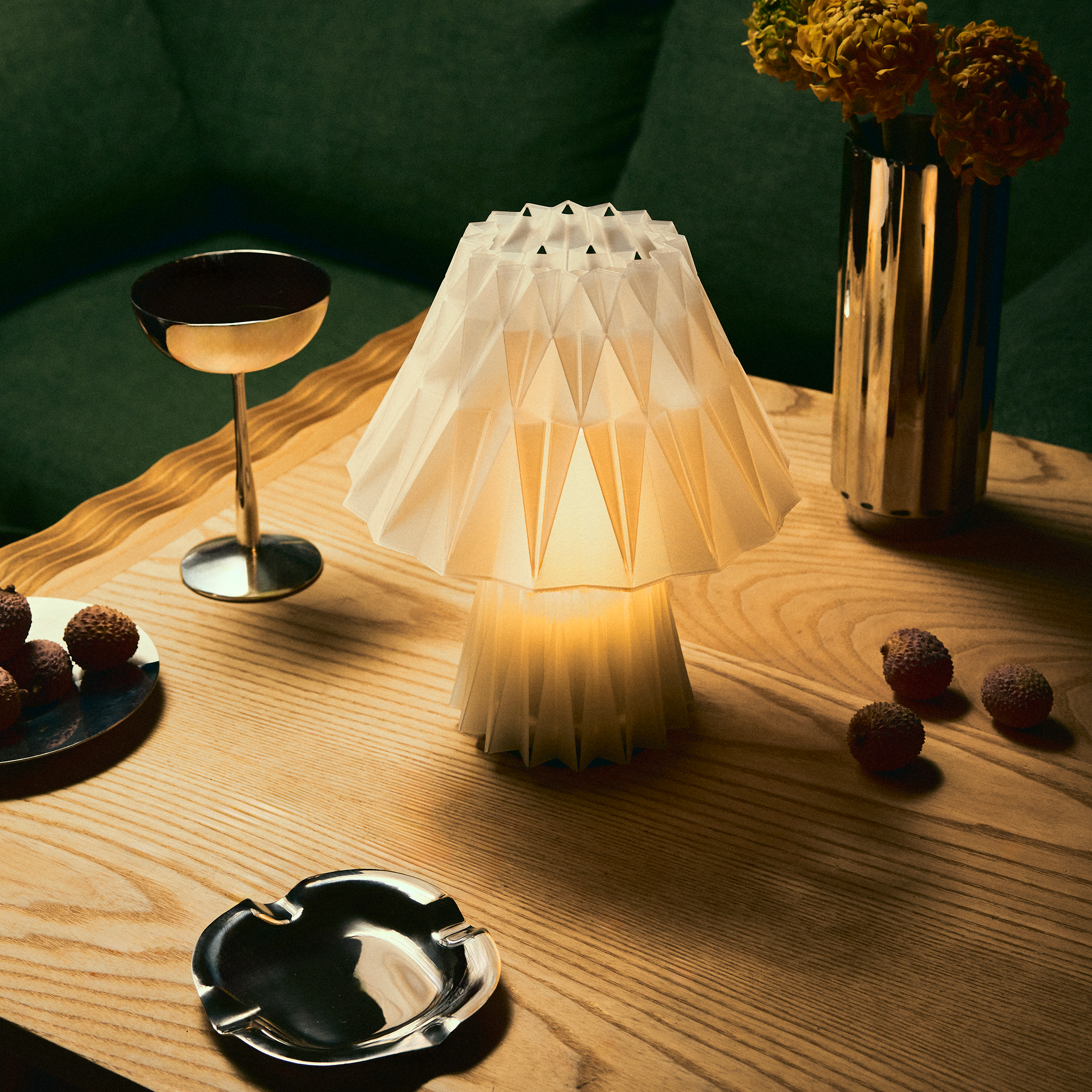 Decorative lamp on a wooden table with a cocktail glass, ashtray, and small plants.