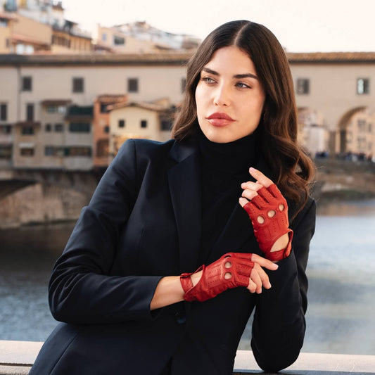 Woman wearing red gloves and a black coat with a bridge and buildings in the background