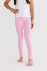 Person wearing pink leggings and a white top on a light gray background