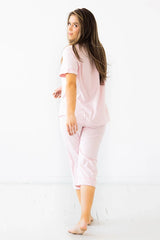 Woman wearing a light pink pajama set on a white background