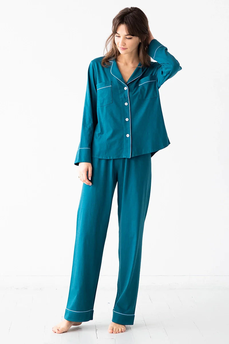 Woman wearing teal pajamas with white piping on a white background