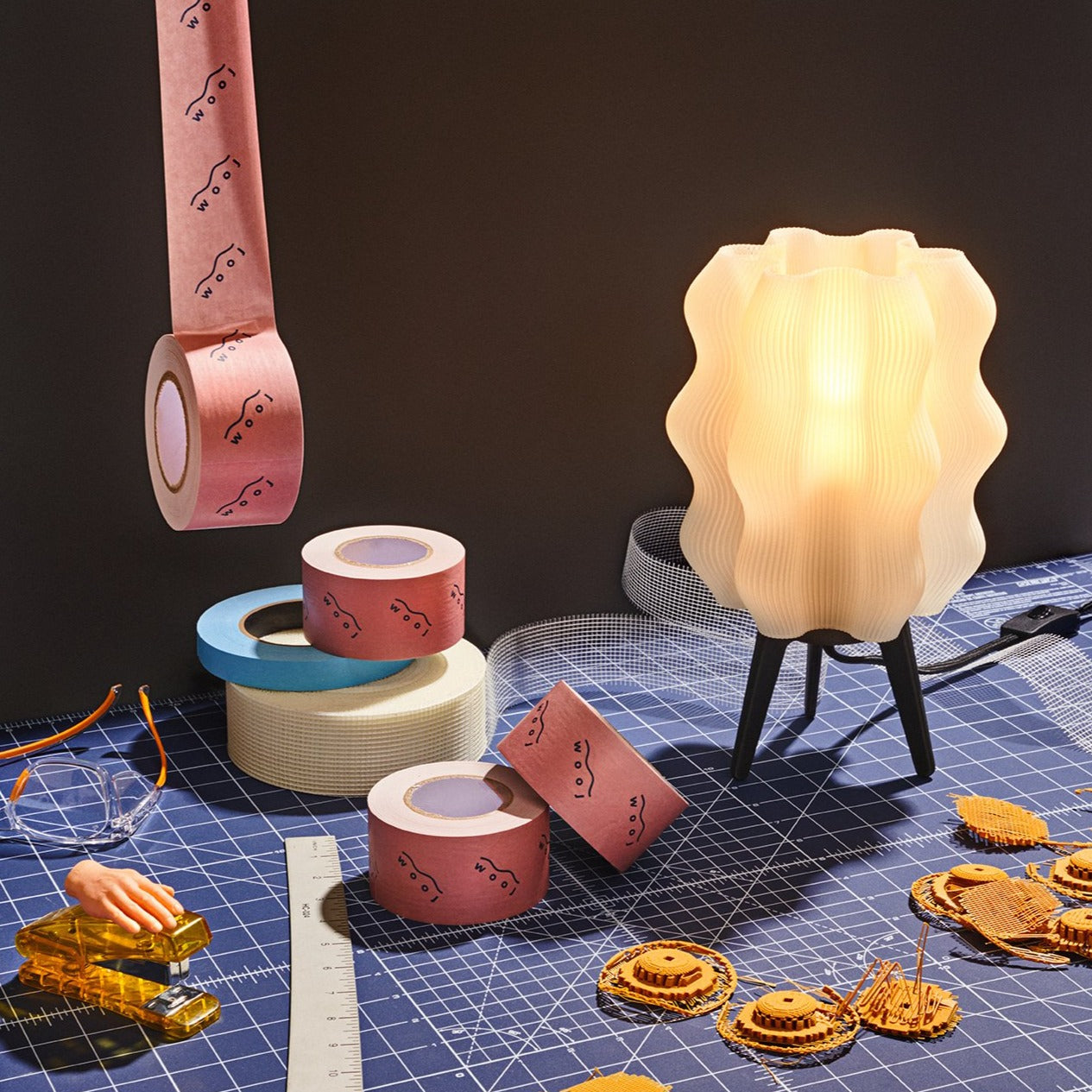 Decorative tape rolls and a lamp on a grid surface with small models.