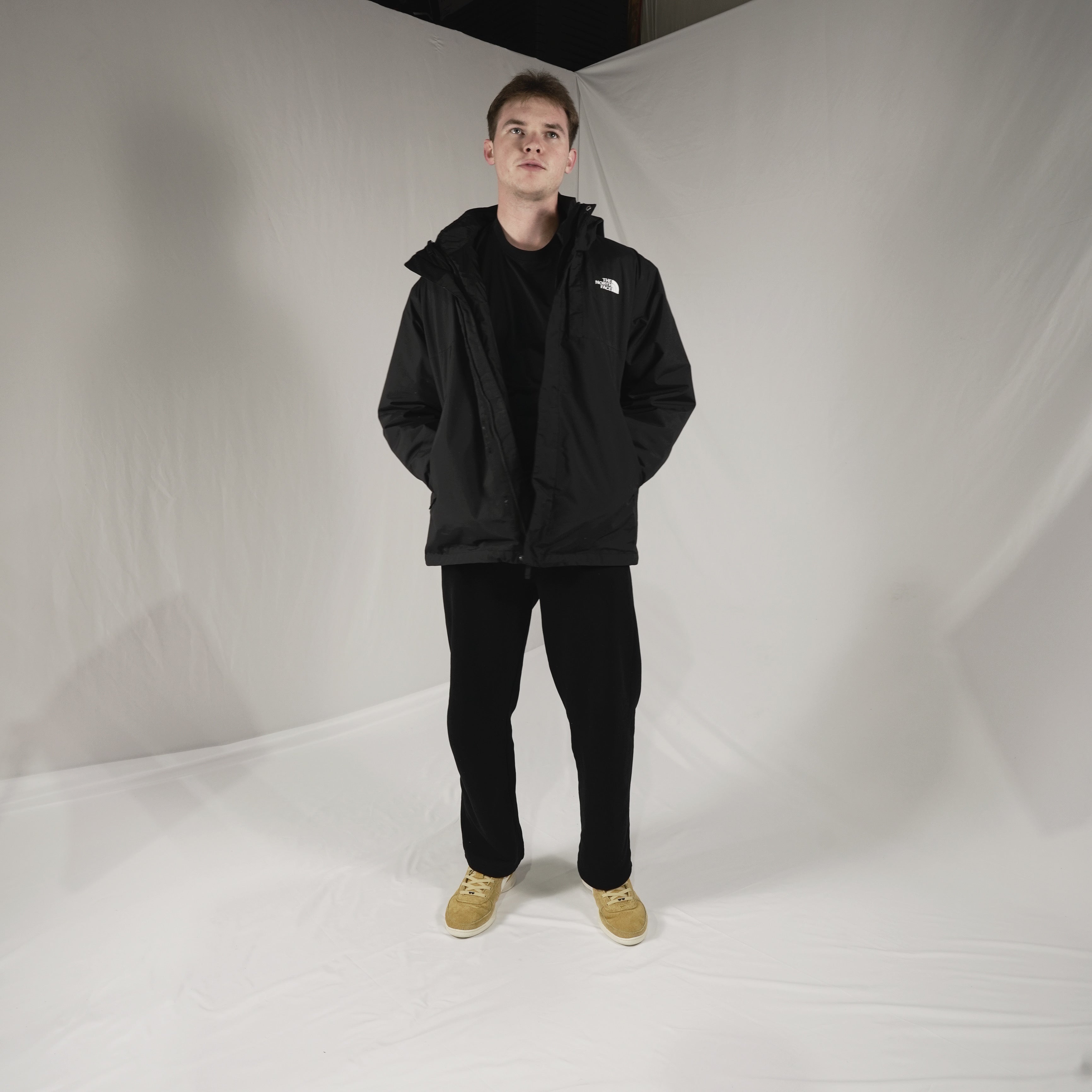 Person wearing a black jacket with a brand logo on a white background