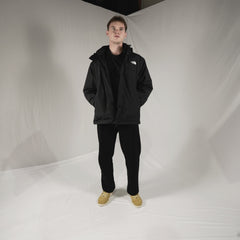 Person wearing a black jacket with a brand logo on a white background