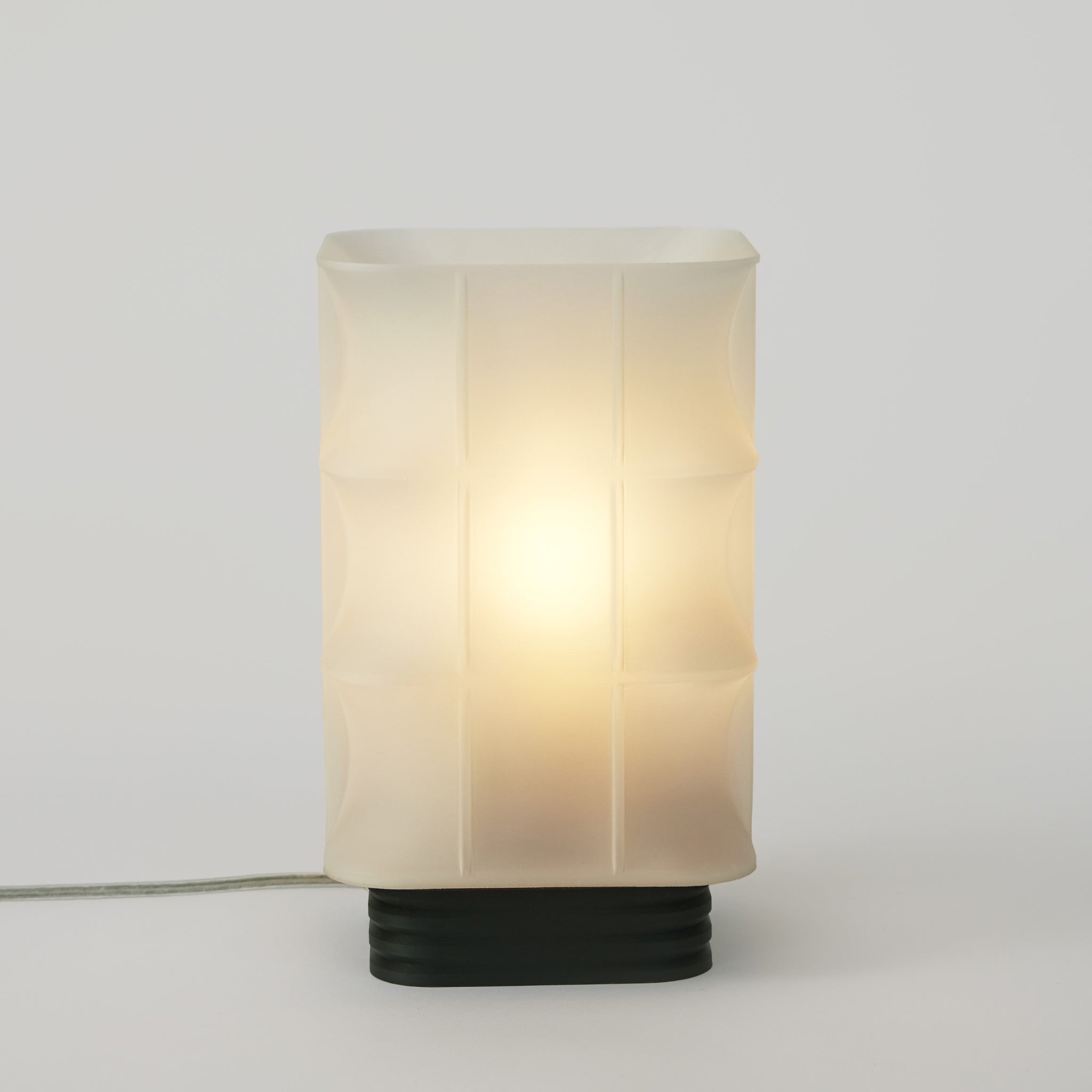 Table lamp with a white glass shade and black base on a light gray background
