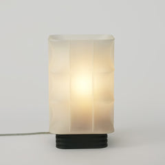 Table lamp with a white glass shade and black base on a light gray background