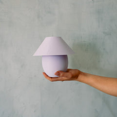 Hand holding a small purple lamp against a gray background