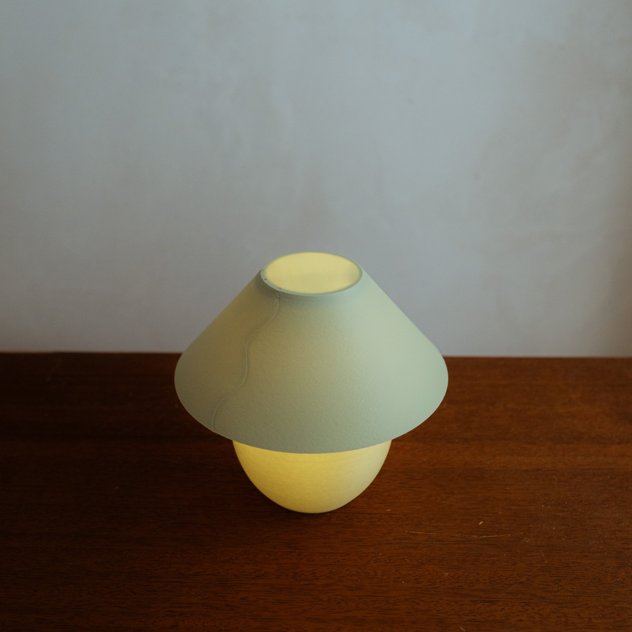 Mushroom-shaped lamp with green top and yellow bottom on a wooden surface.