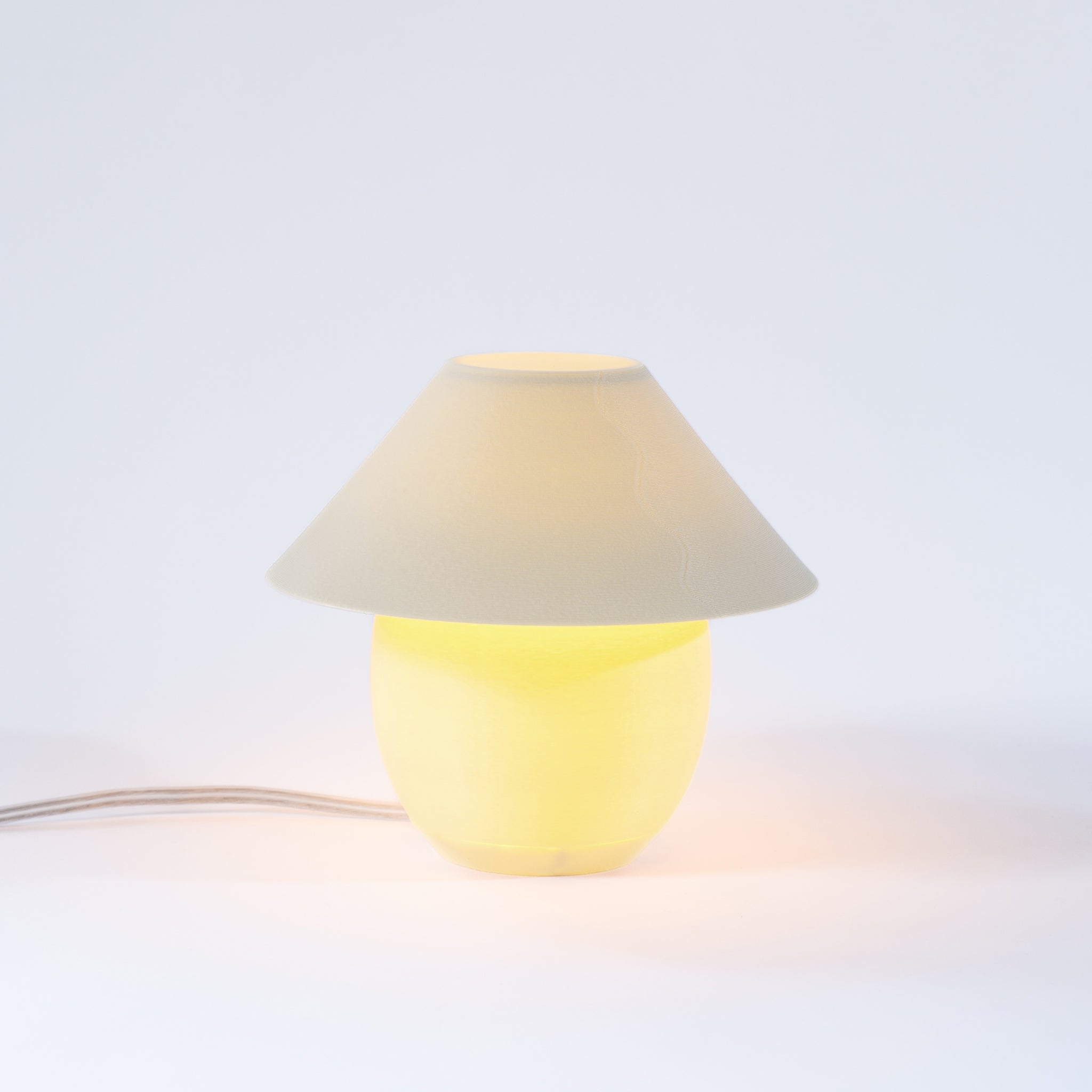 Small lamp with a beige shade and yellow base on a light gray background