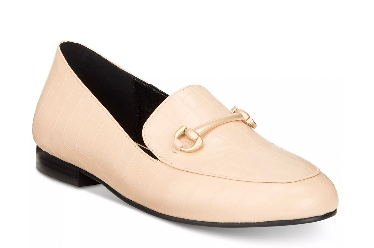 Beige loafer shoe with a gold buckle on a white background