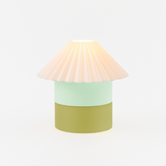 Table lamp with a pastel pink shade, light green middle section, and green base on a white background