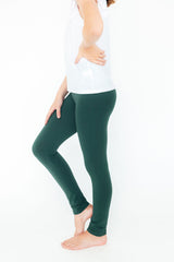 Person wearing green leggings and a white top on a white background