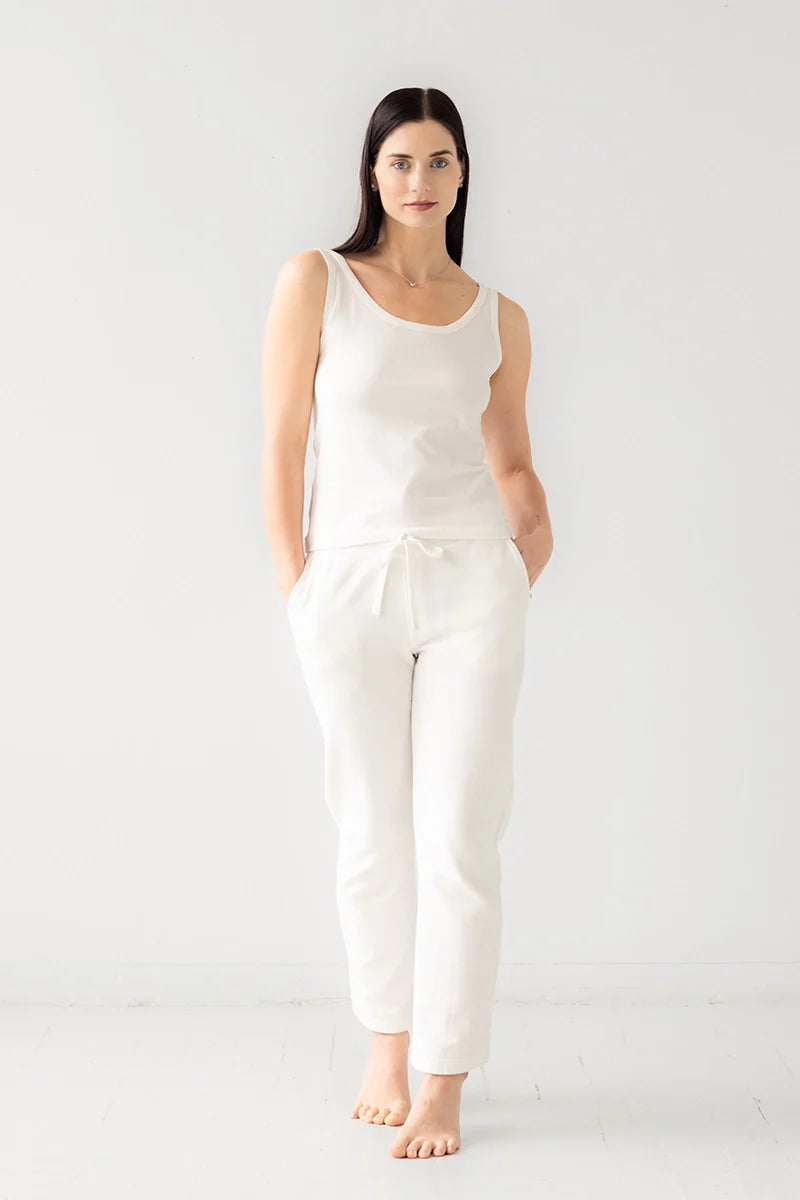 Woman wearing a white sleeveless top and pants on a white background