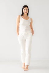 Woman wearing a white sleeveless top and pants on a white background