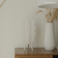White textured lamp and vase on a wooden surface with a neutral background