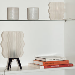 Decorative table lamp with wavy design on a shelf with books