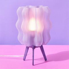 Table lamp with wavy design on a pink surface and purple background