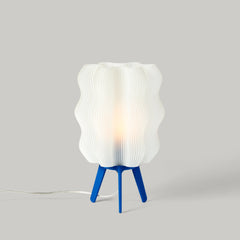 Table lamp with a white ribbed shade and blue base on a gray background