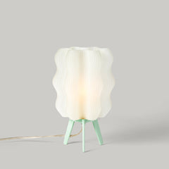 Table lamp with a textured white shade and green base on a gray background