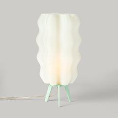 Lamp with a white wavy shade and green base on a gray background