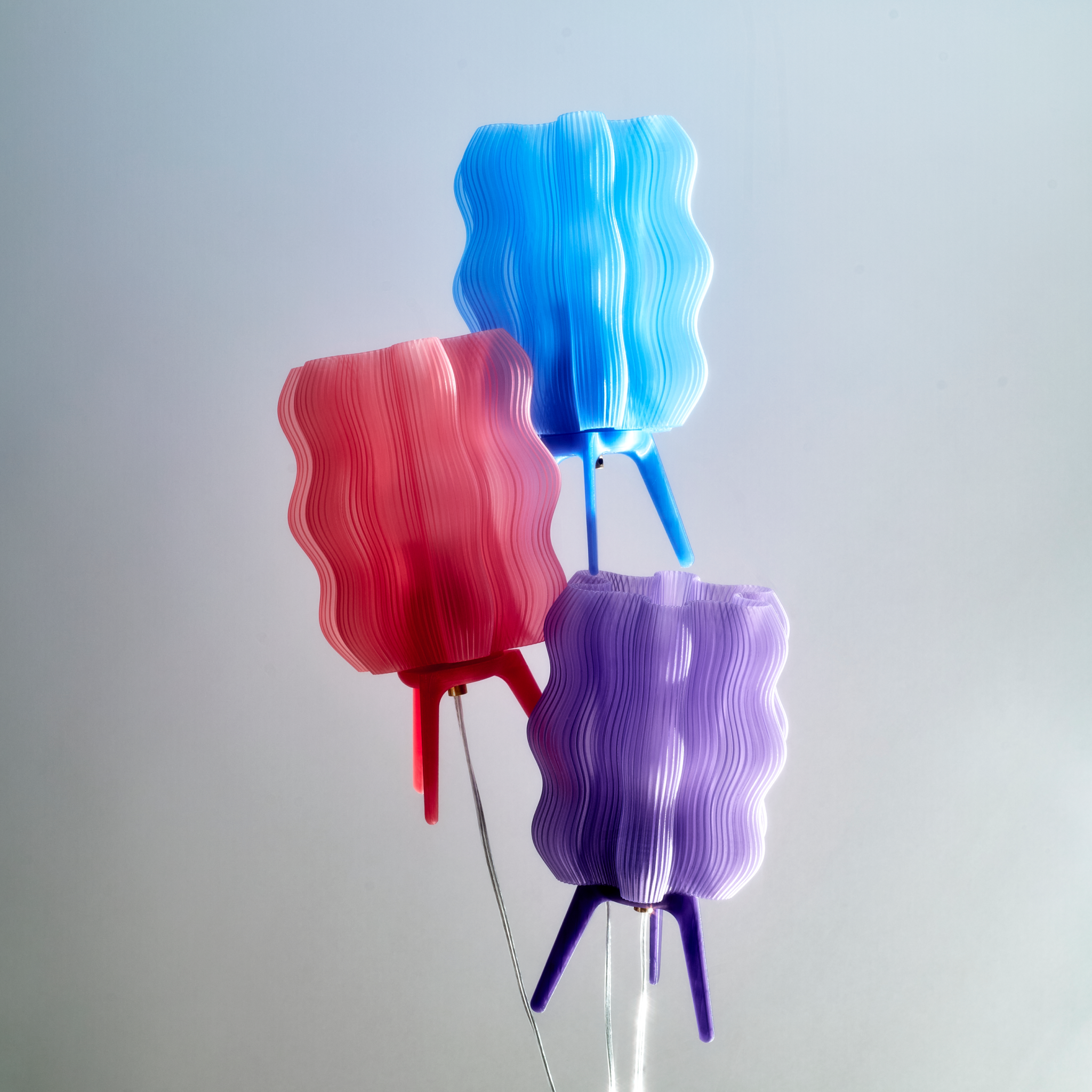 Three colorful lampshades in red, blue, and purple on a gray background