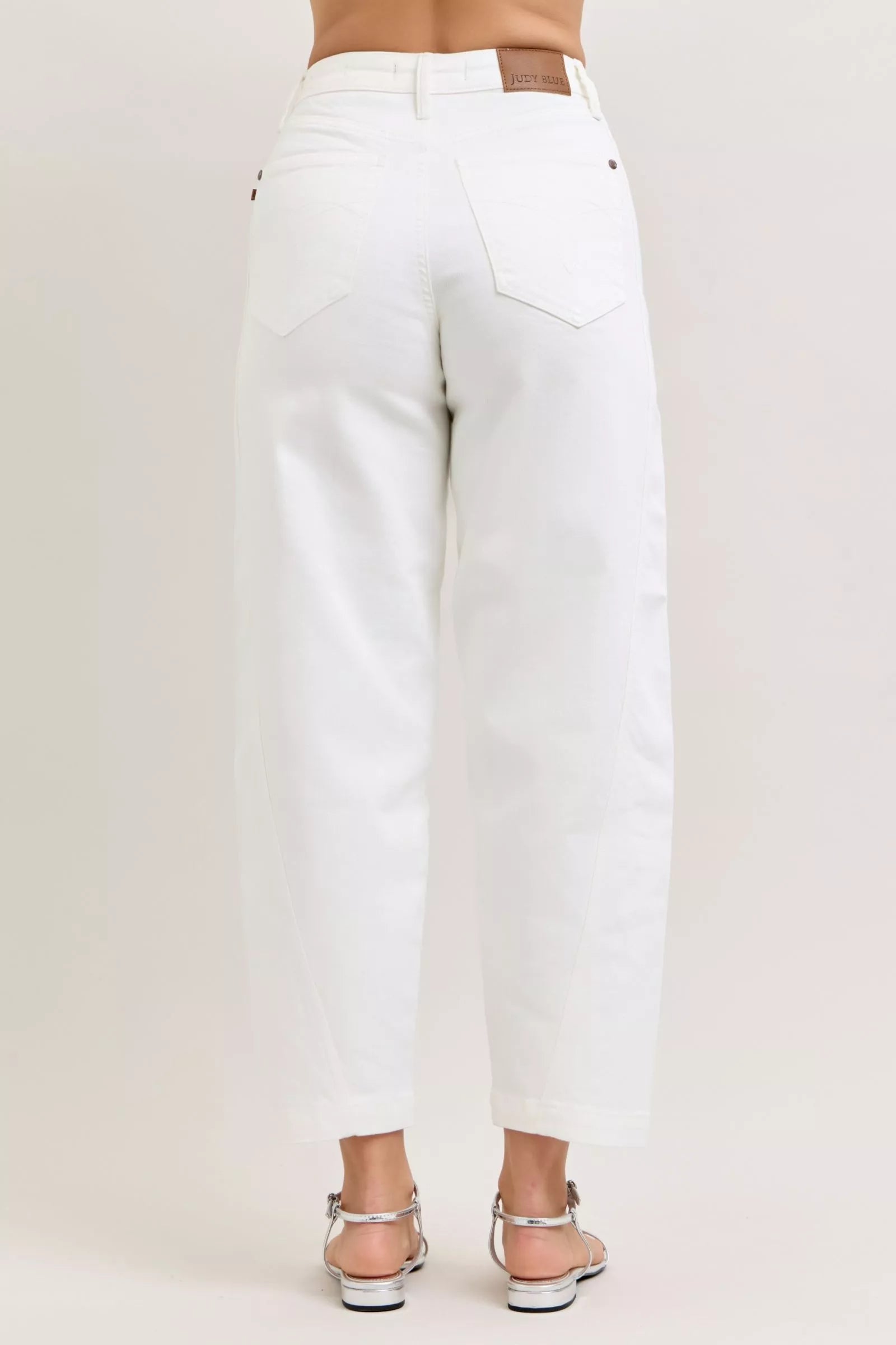White jeans worn by a person on a plain background