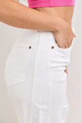 White pants with brown buttons worn by a person on a plain background