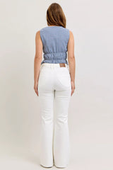 Woman wearing a blue checkered top and white pants on a plain background