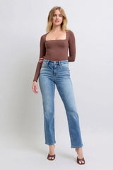 Woman wearing a brown long-sleeve top and light blue jeans on a white background