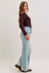 Woman wearing a brown top and light blue jeans on a plain background