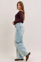 Woman wearing light blue jeans and a dark top on a white background