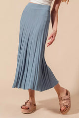 Person wearing a blue pleated skirt on a beige background