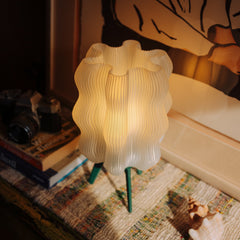 Decorative lamp on a textured surface with books and a camera in the background