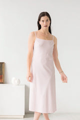 Woman wearing a light pink slip dress against a white background