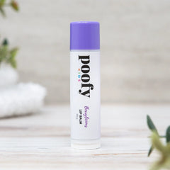Lip balm with purple cap and white body on a light wooden surface