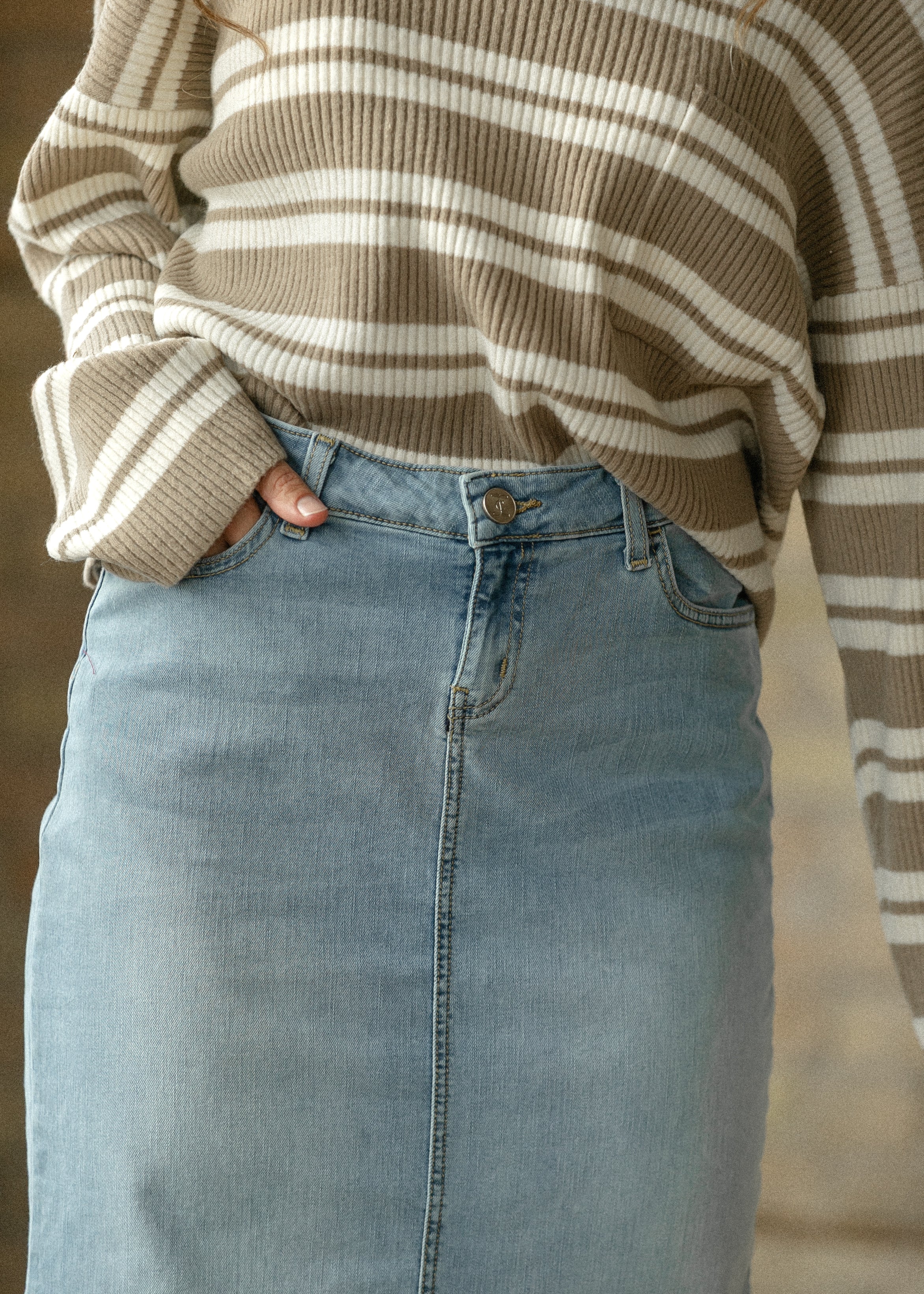 Person wearing a brown and white striped sweater and light blue jeans.