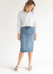 Woman wearing a light blue denim skirt and white shirt on a white background