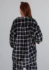 Person wearing a black and white checkered shirt and pants on a gray background
