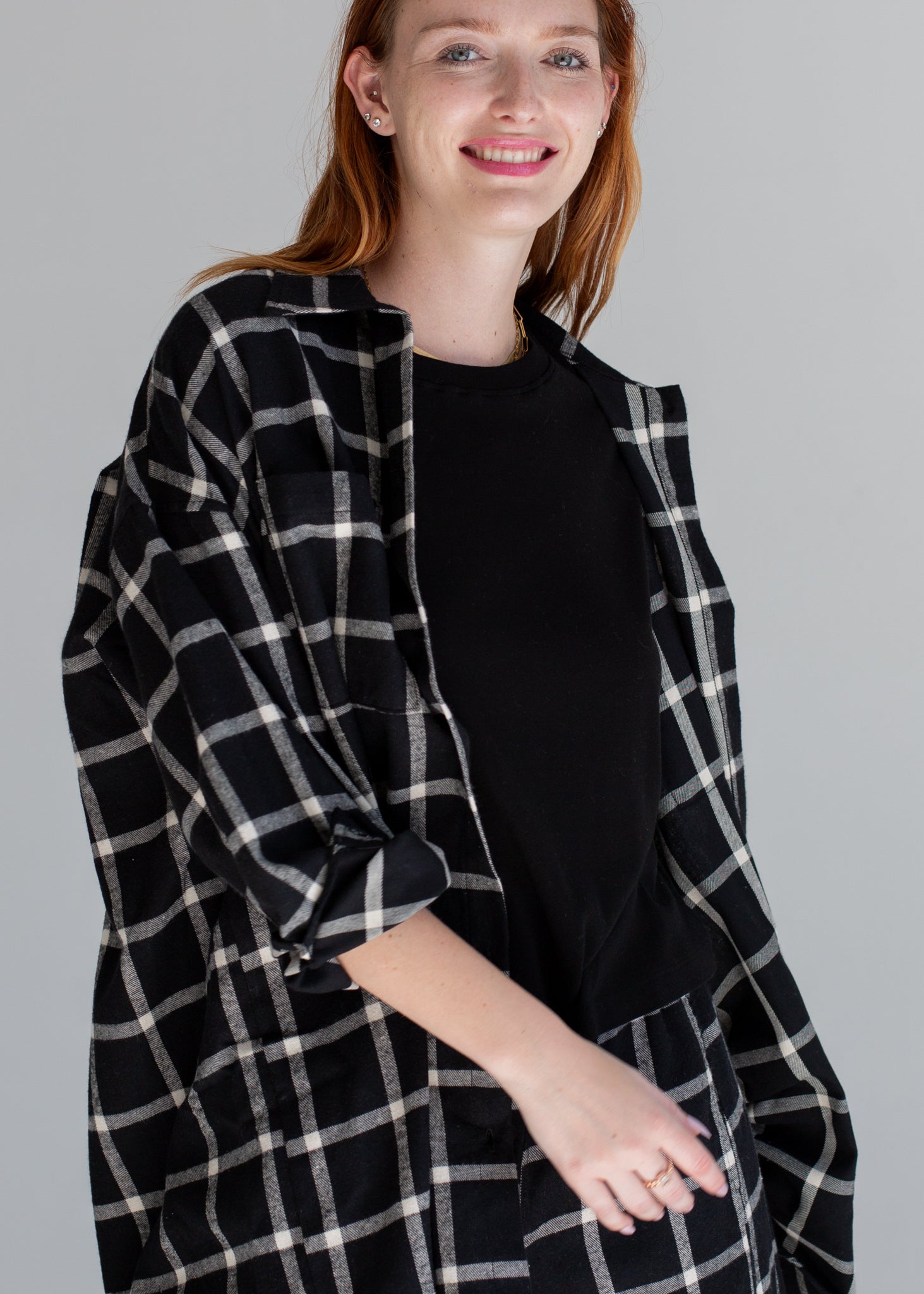 Woman wearing a black and white checkered coat against a gray background