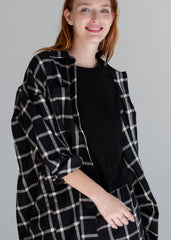 Woman wearing a black and white checkered coat against a gray background
