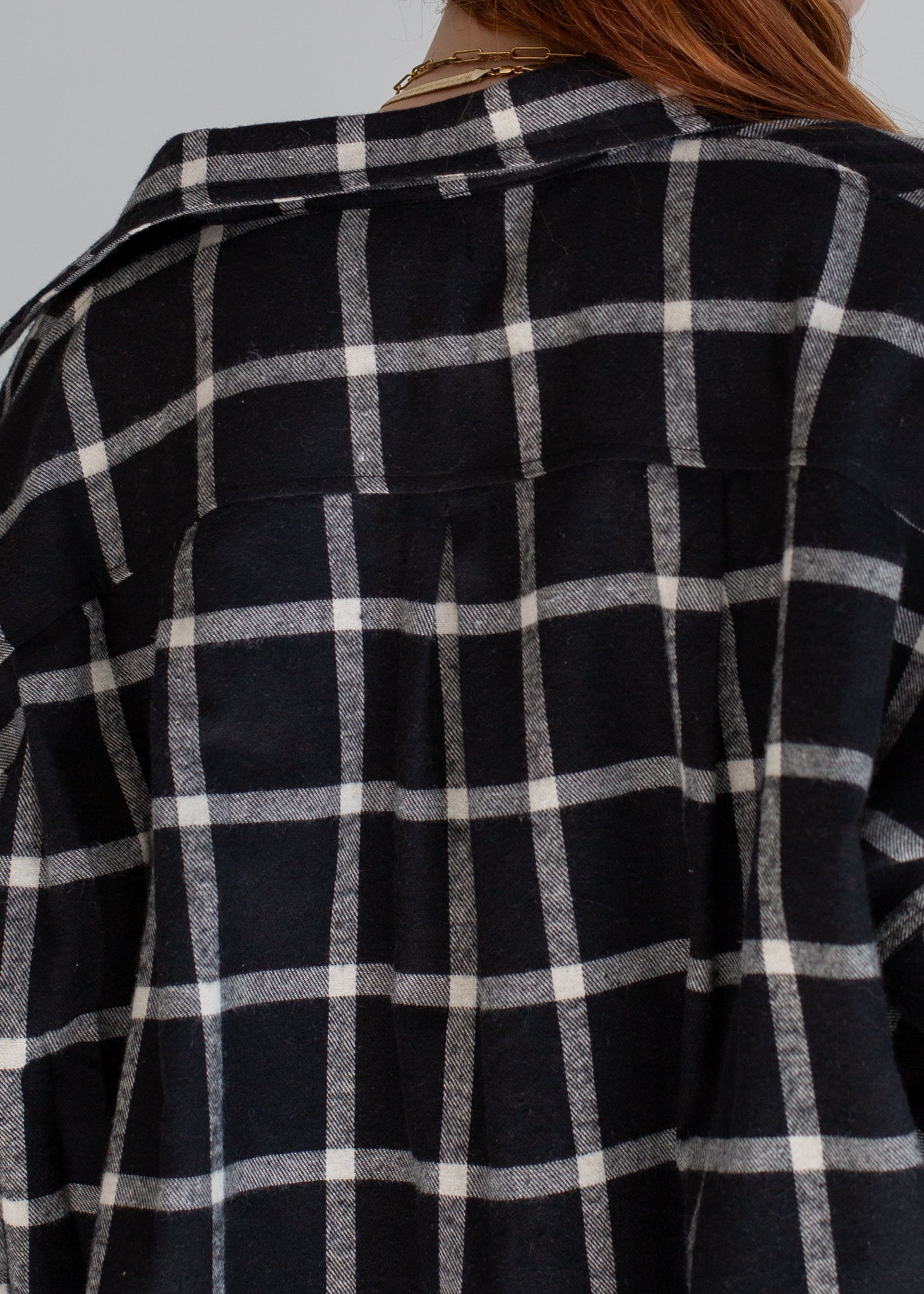 Black and white checkered shirt worn by a person with a neutral background