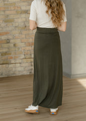 Person wearing a long green skirt with a neutral background