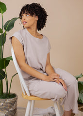Woman sitting on a chair in a neutral setting with plants